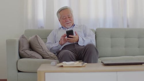 Mature Man Using Smartphone on Couch at Home