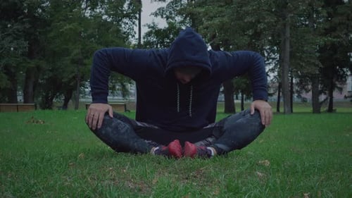 Man Stretching Outside on Green Grass in a Park