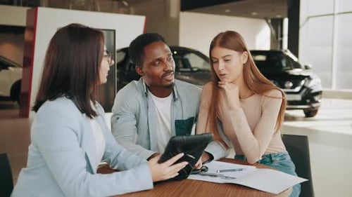 Salesperson Showing Car Features to Couple on Tablet