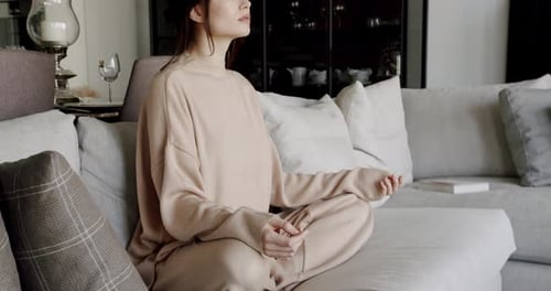 Woman Meditating on Couch in Modern Home