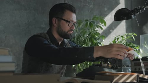 A Man Works on a Typewriter, Takes Out a Sheet of Paper