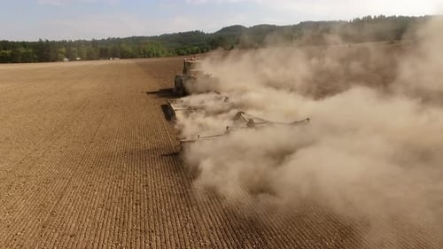 Tractor plowing dusty field aerial view