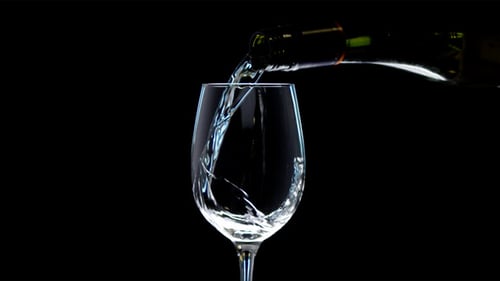 Slow Motion of Pouring White Wine Into the Glass. Liquid Is Poured out Of a Green Bottle. Red Camera