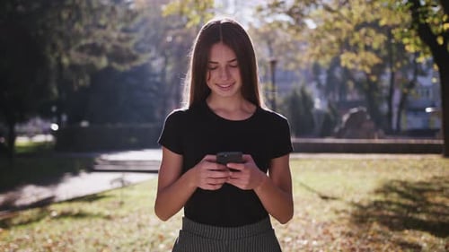An Attractive Young Lady Using a Phone in Town. Medium Shot