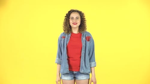 Woman Smiles and Waves on Yellow Background