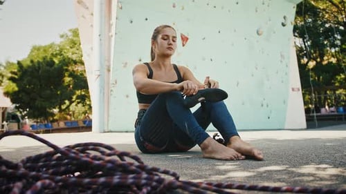 Femme en forme mettant ses chaussures d'escalade se préparant à l'escalade à l'extérieur