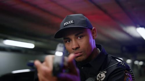 Police Officer Drawing Gun in Dark Garage