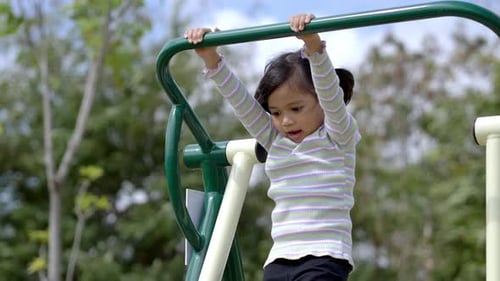 Joyful asian little girl playing exercise equipment in playground
