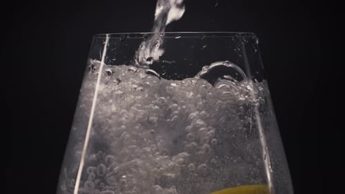 Fizzing Soda Pouring into a Glass with Lemon
