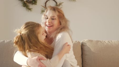 Woman and Child Embrace on the Sofa Indoors