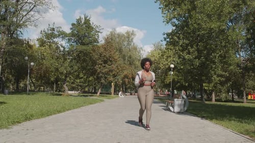 Woman Jogging on Brick Path in Urban Park