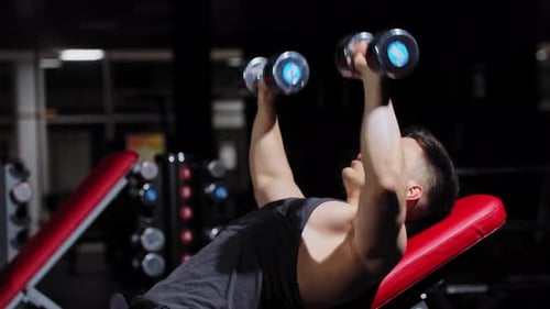 Young Man Lying on an Exercise Equipment and Pumping His Hands