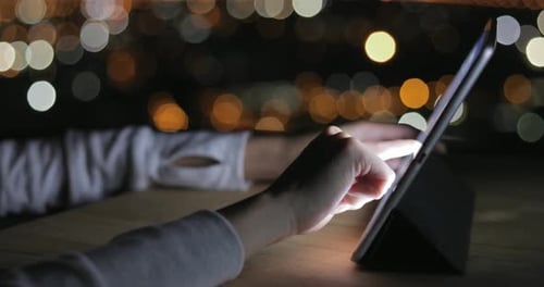Woman Typing on Digital Tablet at Night