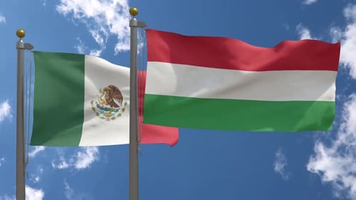 Mexico and Hungary Flags Waving in Wind Against Blue Sky