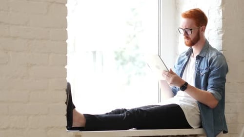 Man with Tablet Relaxing by Bright Window