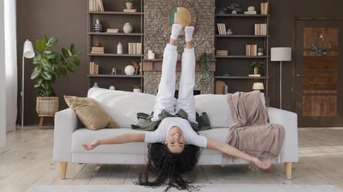 Carefree Happy Young Woman Falls Down on Comfortable Sofa in Living Room Funny Attractive Hispanic