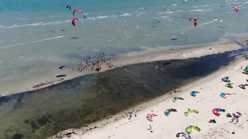Aerial Footage of Many Kitesurfers in the Sea and People Watching Them,