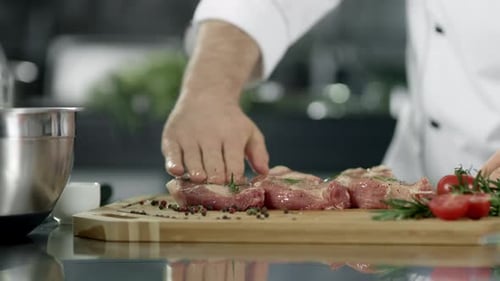 Chef Preparing Raw Meat with Rosemary and Tomatoes