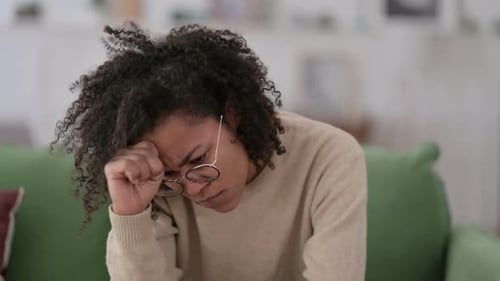 Stressed African Woman with Headache on Sofa