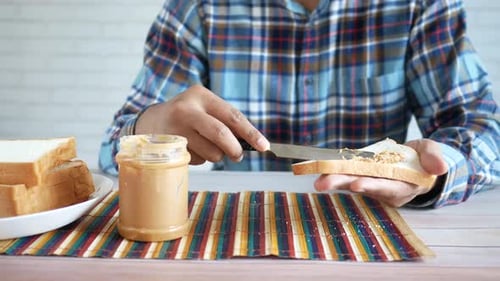Spreading peanut butter on bread