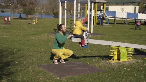 Father and son playing at seesaw in public playground, Zagreb, Croatia.