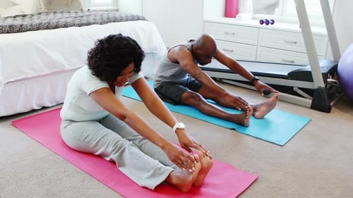 Couple Stretching Together on Yoga Mats Indoors