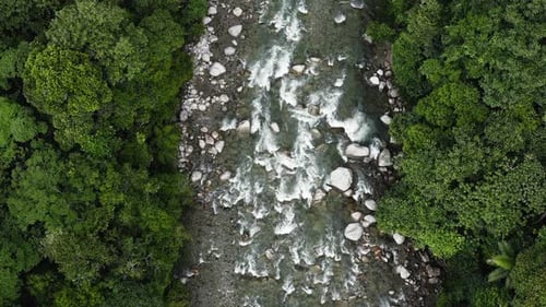 Aerial top down view of a rushing tropical river with a fast current