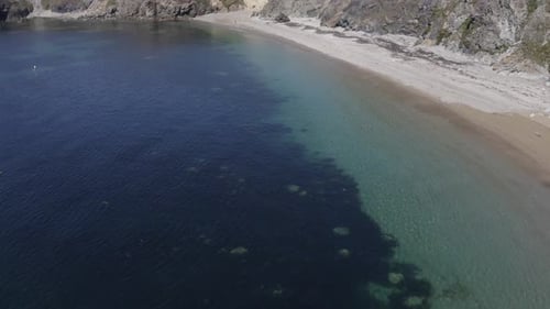 People and dogs enjoy secluded pebble beach and cold clear ocean water