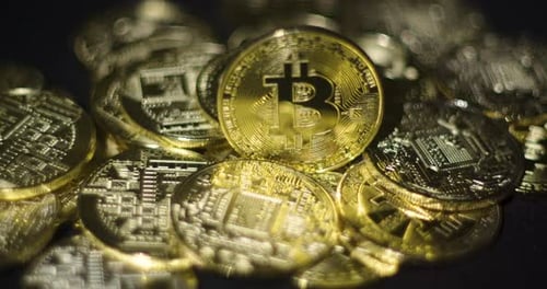 Echte goldene Münzen mit Bitcoin-Logo auf schwarzem Hintergrund