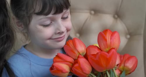 Happy Child Smelling a Bouquet of Tulips