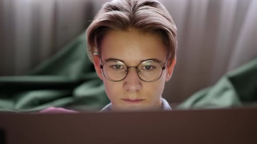 Teen Focused on Computer Screen in Bedroom