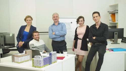 Workmates Stand Together in the Office Over the Model of Houses and Smile