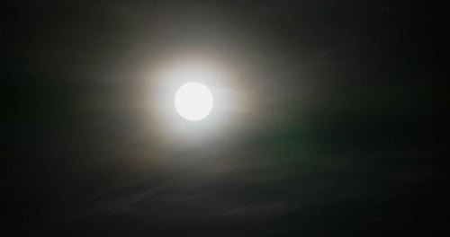Glowing Moon Surrounded by Clouds in Night Sky