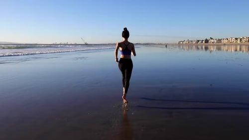 Slow motion shot of an Asian woman jogging on the beach