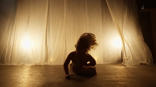 Silhouette of a Professional Dancer Performing in Studio in Soft Warm Lighting