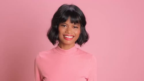Smiling Young Woman in Front of Pink Backdrop