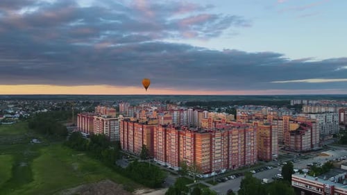 Air balloon festival in the evening city. It floats in the distance above houses