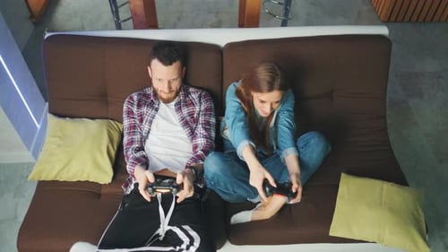 A Couple of Young Adults is Playing Video Games at Home