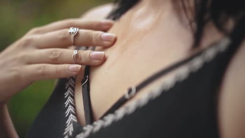 Gros plan d'une jeune femme transpirant par une chaude journée. Femme touchant doucement sa poitrine avec les doigts en mouvement