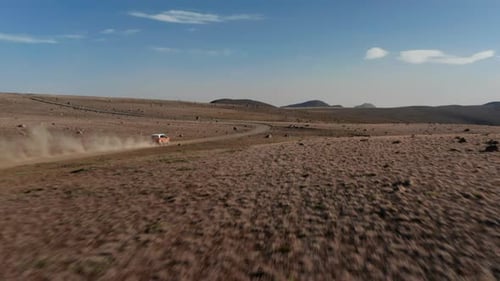 Drohne mit Luftaufnahme folgt einem Auto, das eine große Staubwolke aufwirbelt, während es die Desert Road entlang