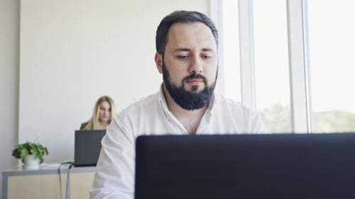 Jeune employé regardant un écran d'ordinateur pendant une journée de travail au bureau