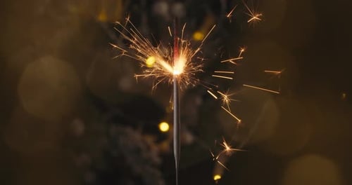 Festive Sparkler Burning with Christmas Lights Background