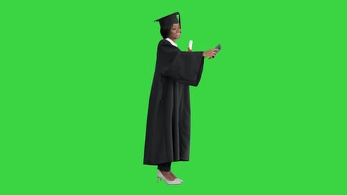 Happy African American Female Graduate Holding Diploma and Making Selfie on a Green Screen, Chroma