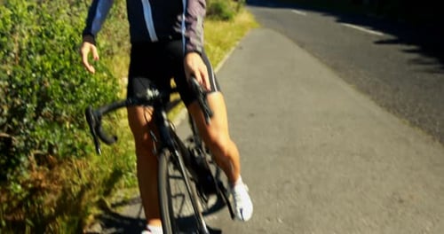 Female cyclist taking break after cycling on countryside road 4k