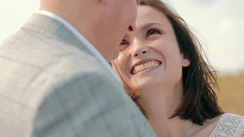 Novio feliz y novia morena sonriendo abrazándose en verano al aire libre