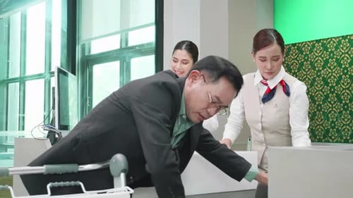 Asian businessman loading her luggage at the check-in counter at airport