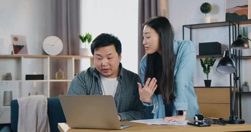 Un couple asiatique travaille ensemble sur un projet de présentation et de révision d'une start-up sur ordinateur