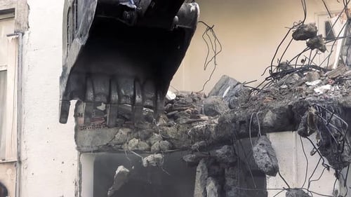 Excavator Demolishing Building in Urban Setting