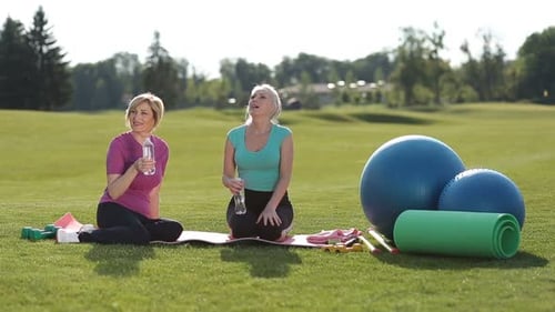 Fit Senior Women Relaxing Drinking Water in Park