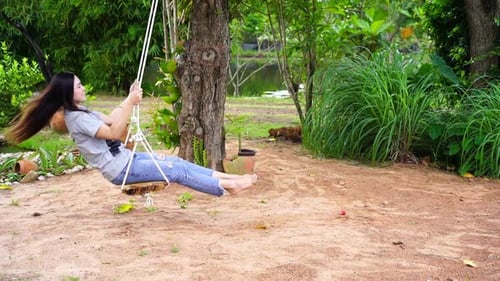 Ralentissement d'une femme jouant sur une balançoire dans le jardin
